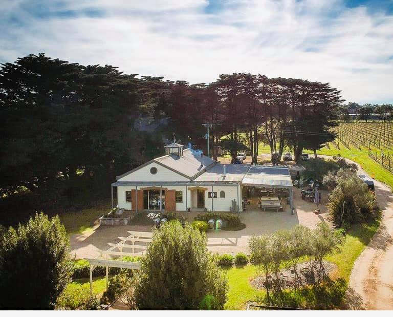 An aerial view of a white house surrounded by trees