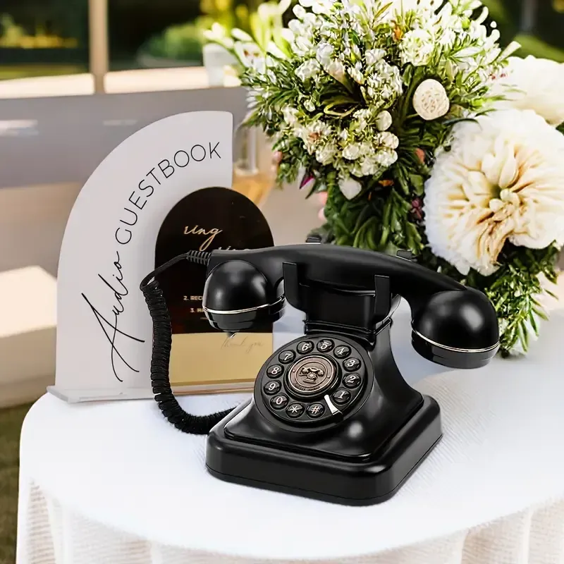 A black telephone is sitting on a table next to a guestbook