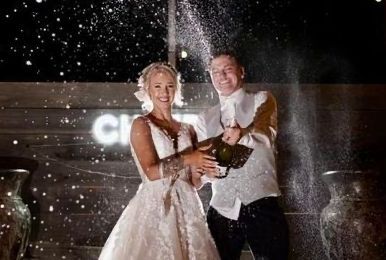 A woman in a wedding dress is playing music on a laptop.