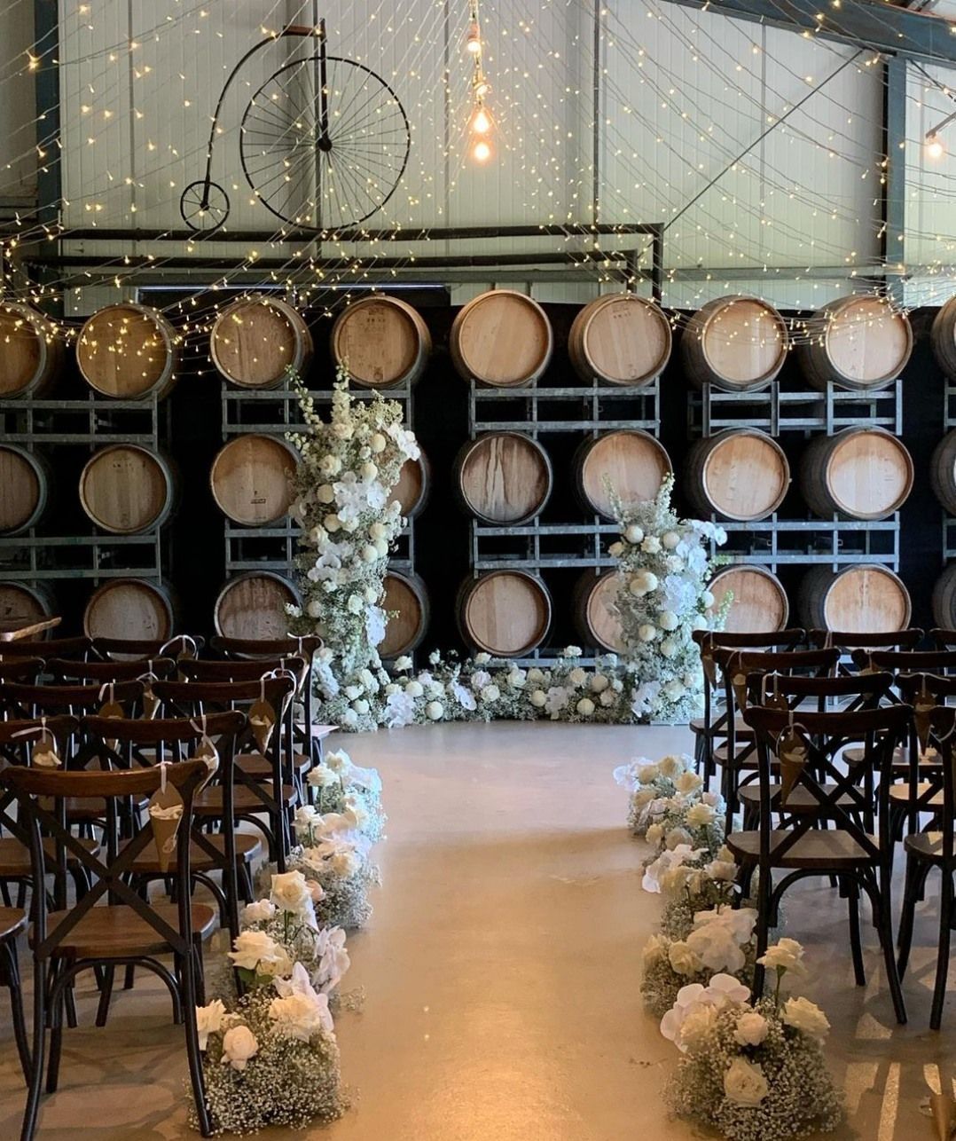 A row of chairs are lined up in front of a row of wine barrels.