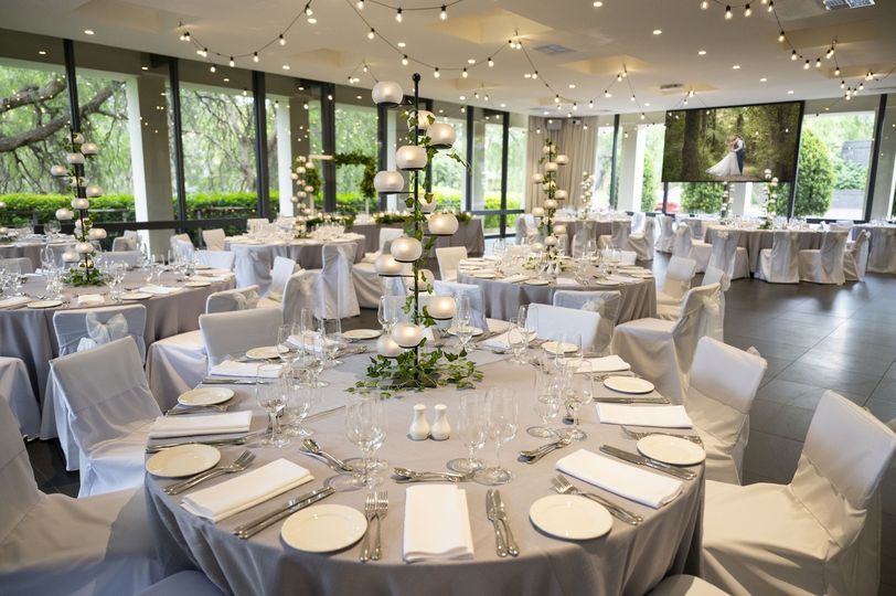 A large room filled with tables and chairs set up for a wedding reception.