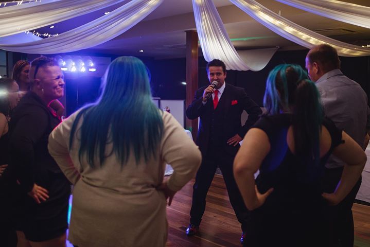 A group of people are standing around a man holding a microphone.