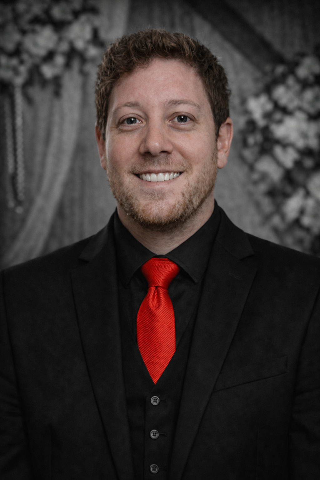 Man in suit smiling, red tie, pocket square. Beige background with sketched effect.