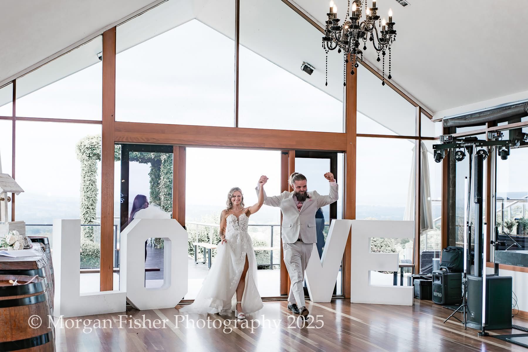 A bride and groom are standing in front of a large love sign.