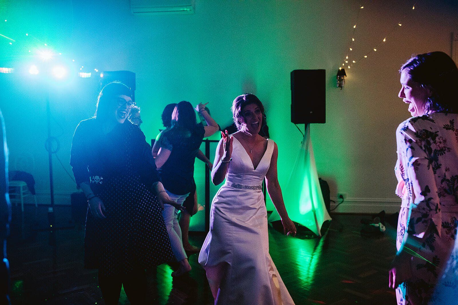 A group of people are dancing in a room with green lights.