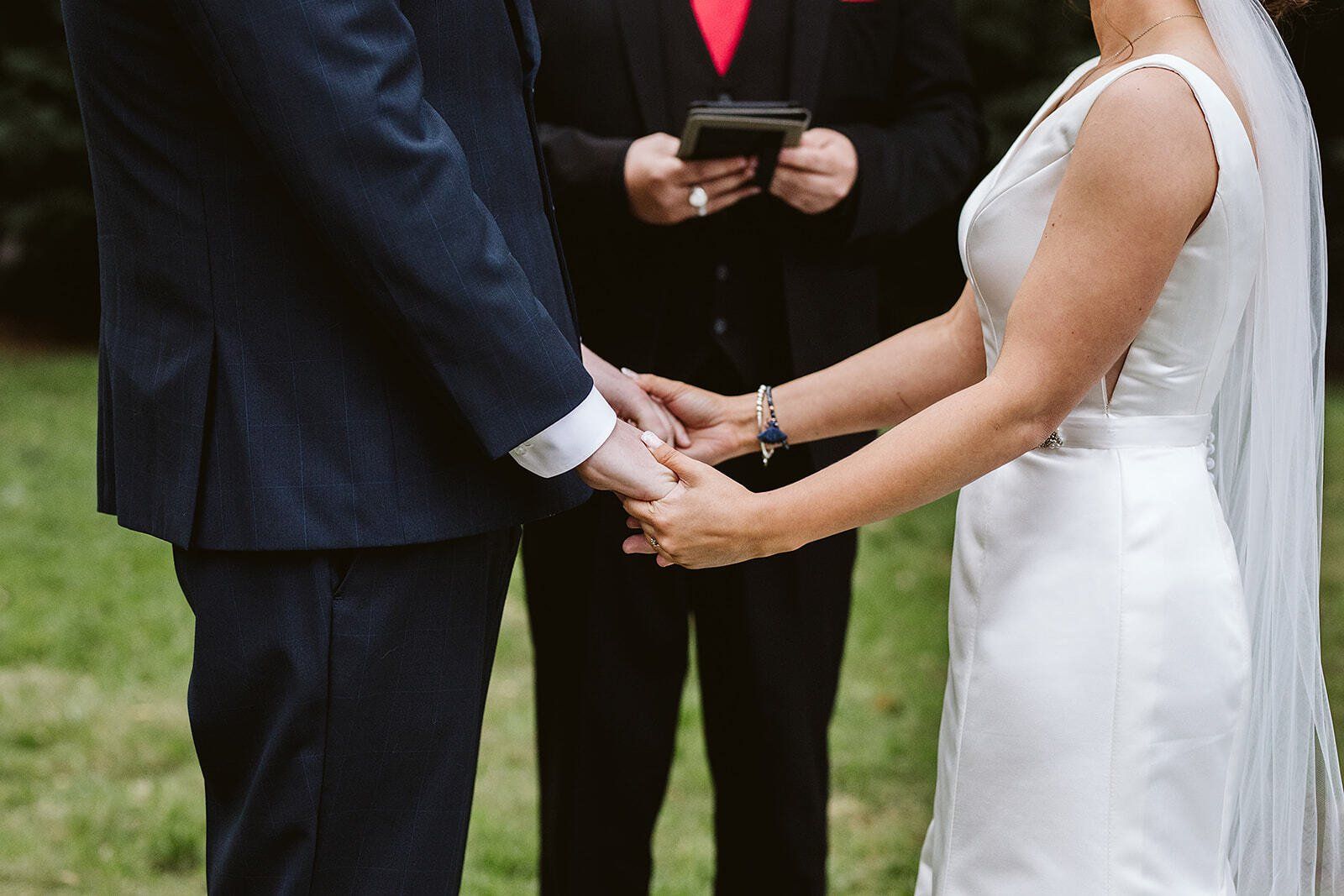 A bride and groom are holding hands during their wedding ceremony.