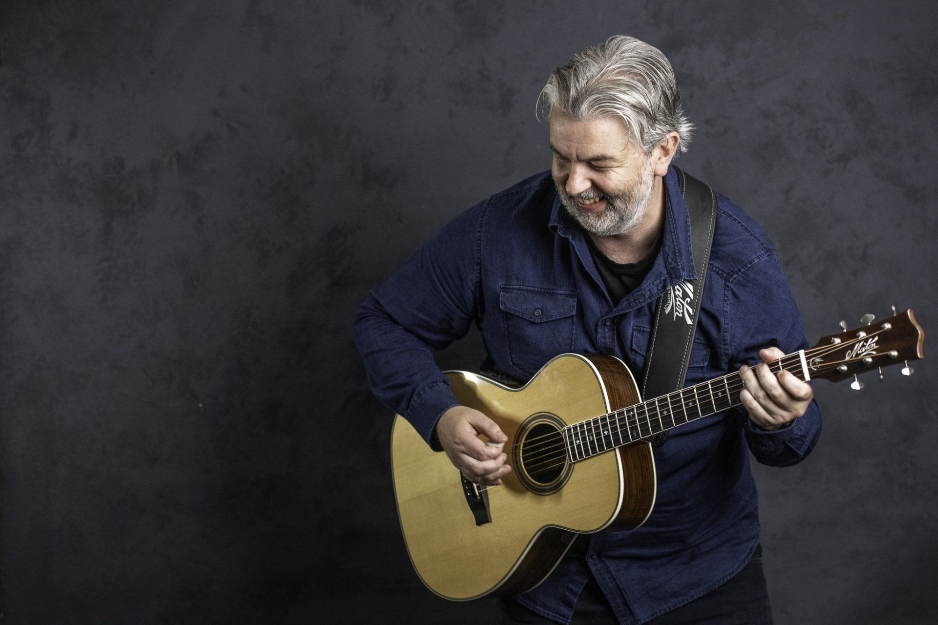A man with a beard is playing an acoustic guitar.