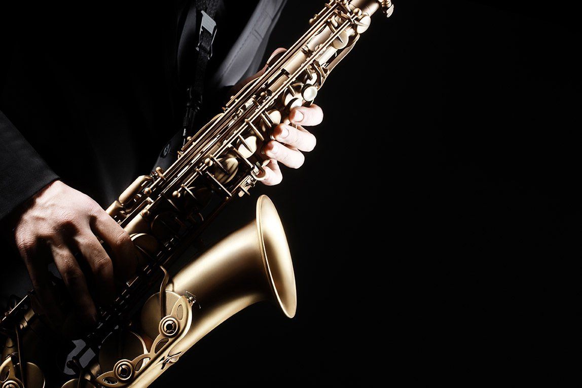 A man is playing a saxophone in a dark room.