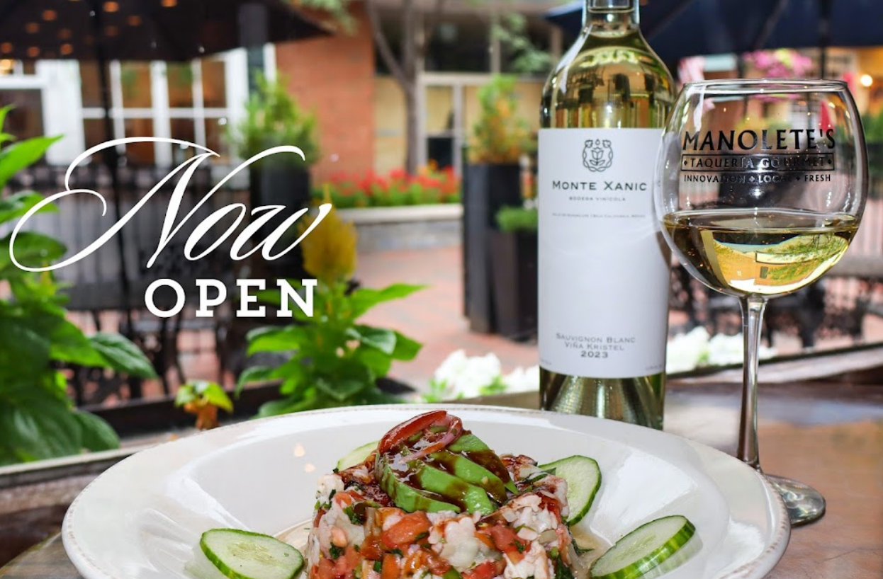 A bottle of wine and a glass of wine are on a table next to a plate of food.