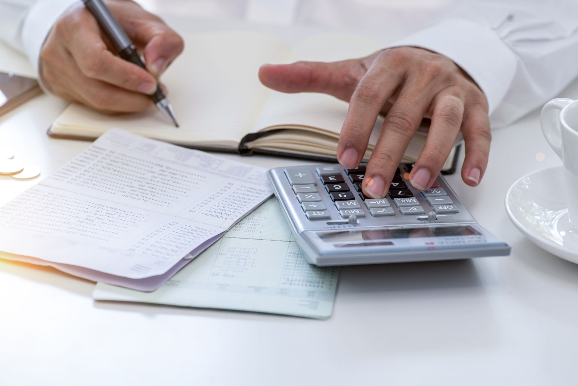 Person using a calculator, surrounded by paperwork, likely working on taxes.