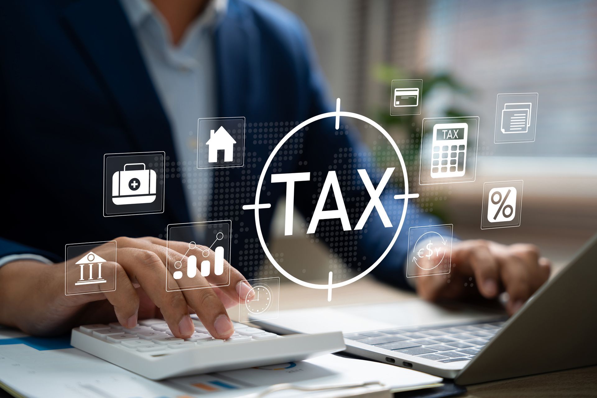 Person in suit calculating taxes on a calculator and laptop.