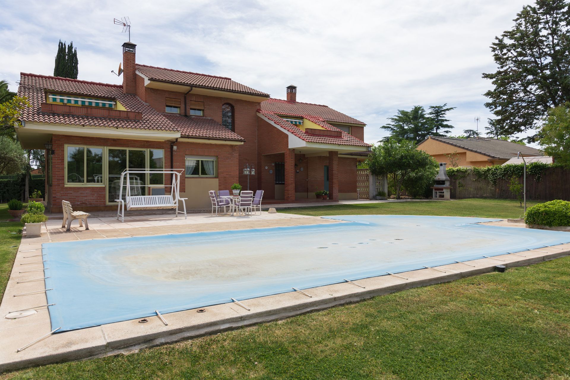 Brick house with covered swimming pool in a landscaped backyard. Brick house with covered swimming pool in a landscaped backyard.