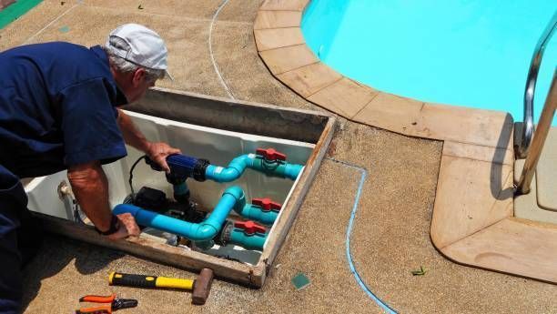 A technician is performing commercial pool repair service near the pool equipment vault with tools.