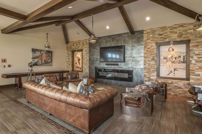 Luxurious living room with brown leather furniture, stone fireplace, and art.
