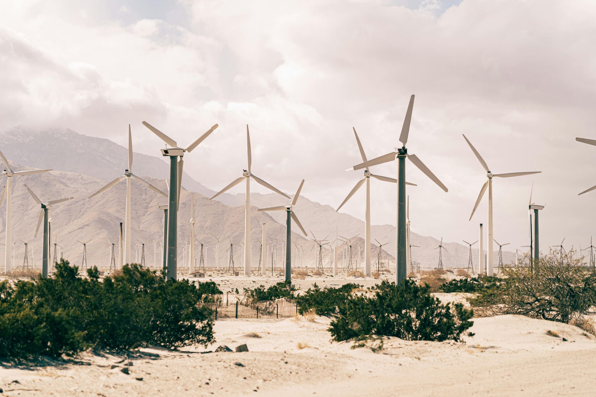 Wind turbines in a desert landscape, generating clean energy under a cloudy sky.
