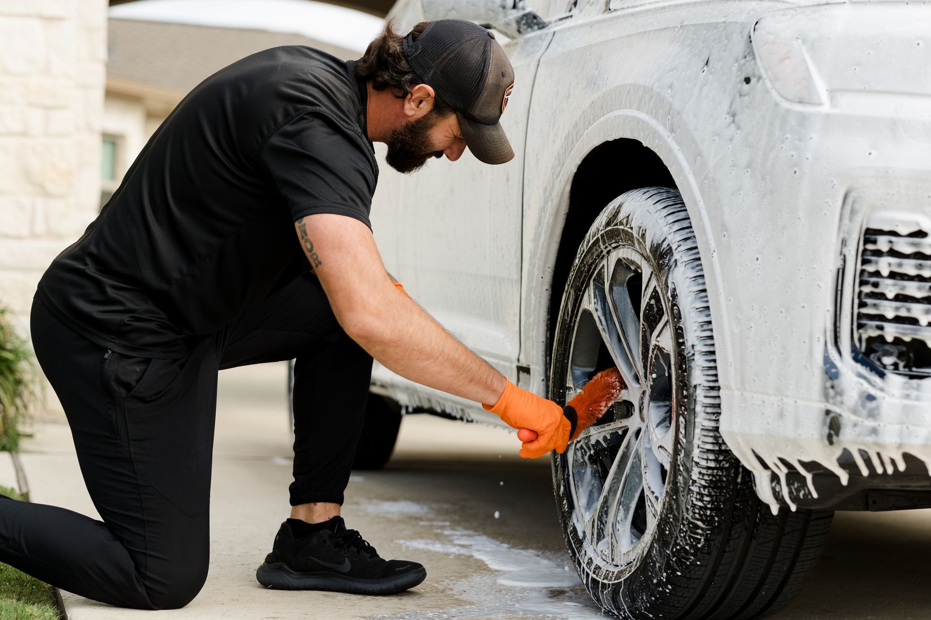 Man scrubbing tires and wheels during mobile car detailing service in Dripping Springs, TX.