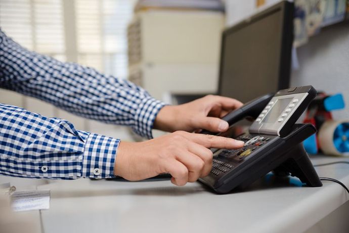 A Man is Using a Telephone in an Office — Ardent Office Equipment in Hermit Park, QLD