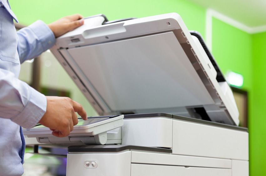 A Man is Using a Copier in an Office — Ardent Office Equipment in Hermit Park, QLD