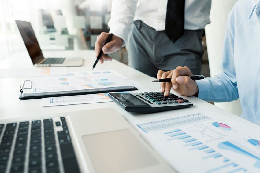 A Man is Using a Calculator While Another Man Stands Behind Him — Ardent Office Equipment in Hermit Park, QLD