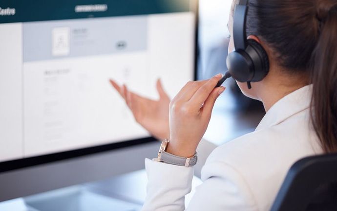 A Woman Wearing a Headset is Sitting in Front of a Computer — Ardent Office Equipment in Hermit Park, QLD