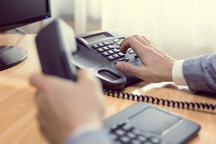 A Person is Dialing on a Telephone While Sitting at a Desk — Ardent Office Equipment in Hermit Park, QLD