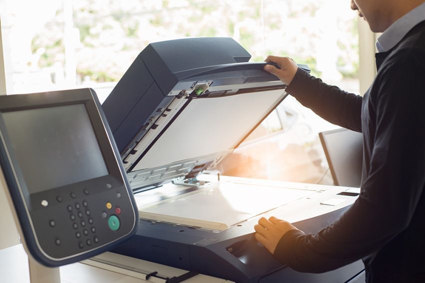 A Man is Using a Photocopier in an Office — Ardent Office Equipment in Ingham, QLD
