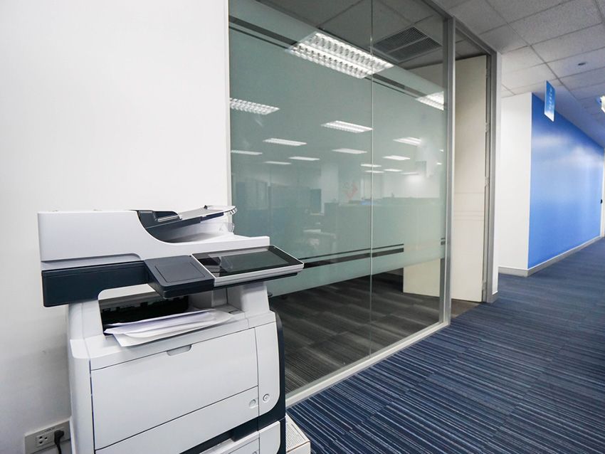 A Printer in a Hallway Next to a Glass Wall — Ardent Office Equipment in Hermit Park, QLD