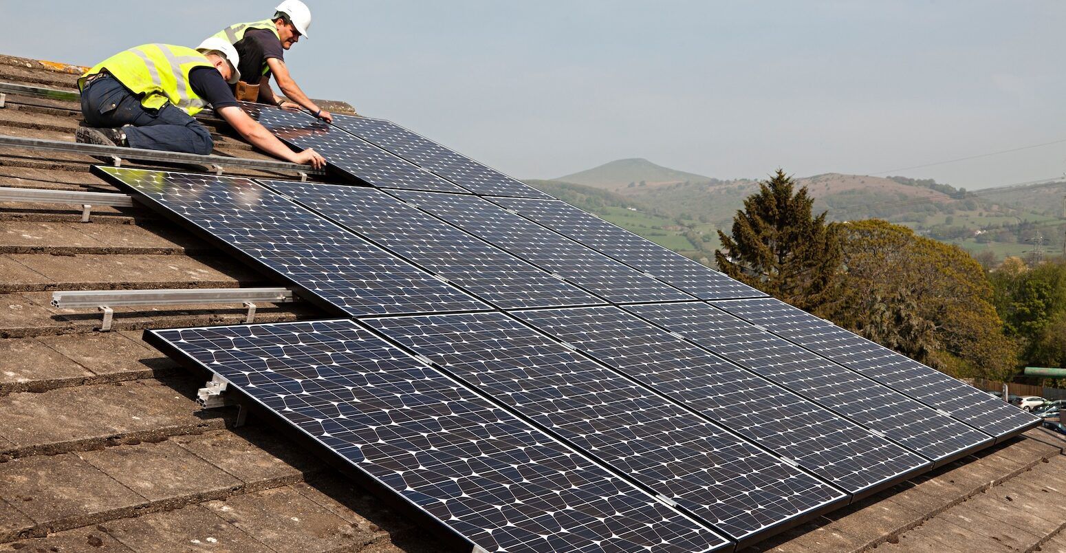 Two men are installing solar panels on a roof