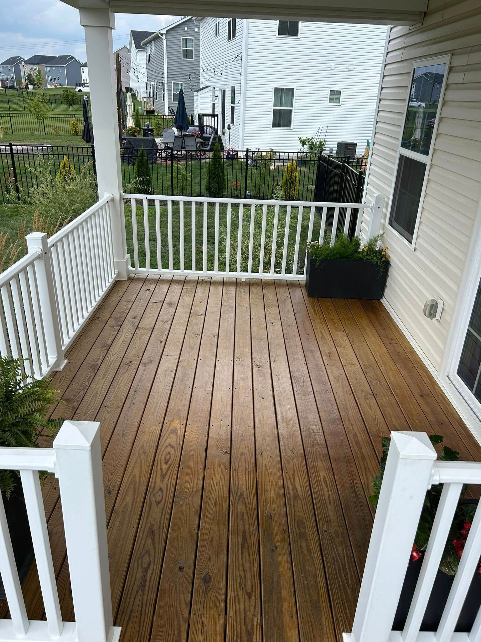 Wooden deck with white railing. View of a backyard with other houses.