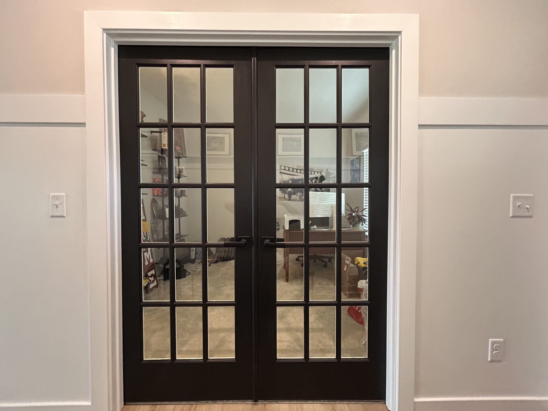 Double black glass paneled doors with white trim, set in a neutral-colored room.