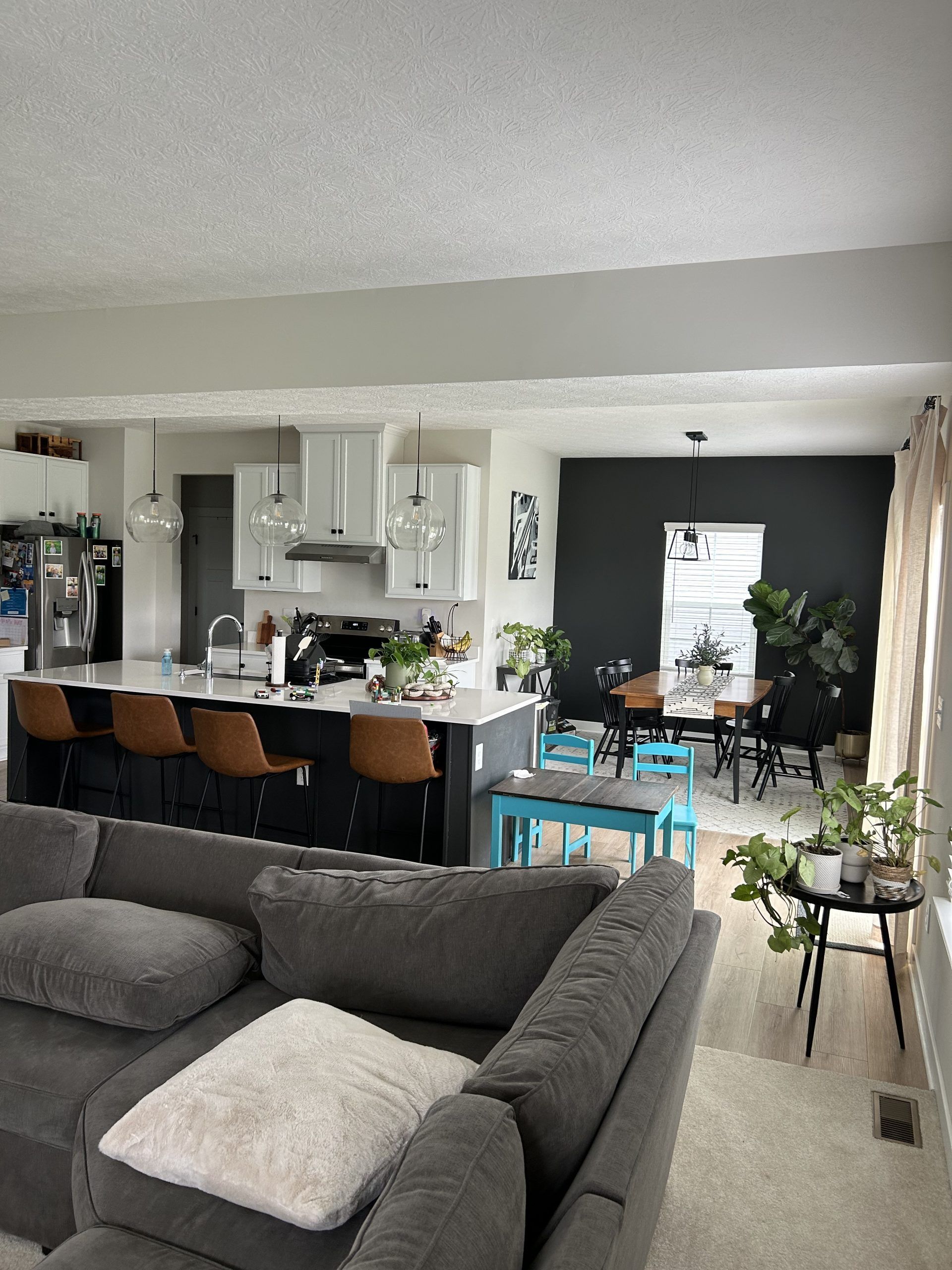 Modern kitchen with a dark island and contrasting white cabinets. A seating area is in the foreground.