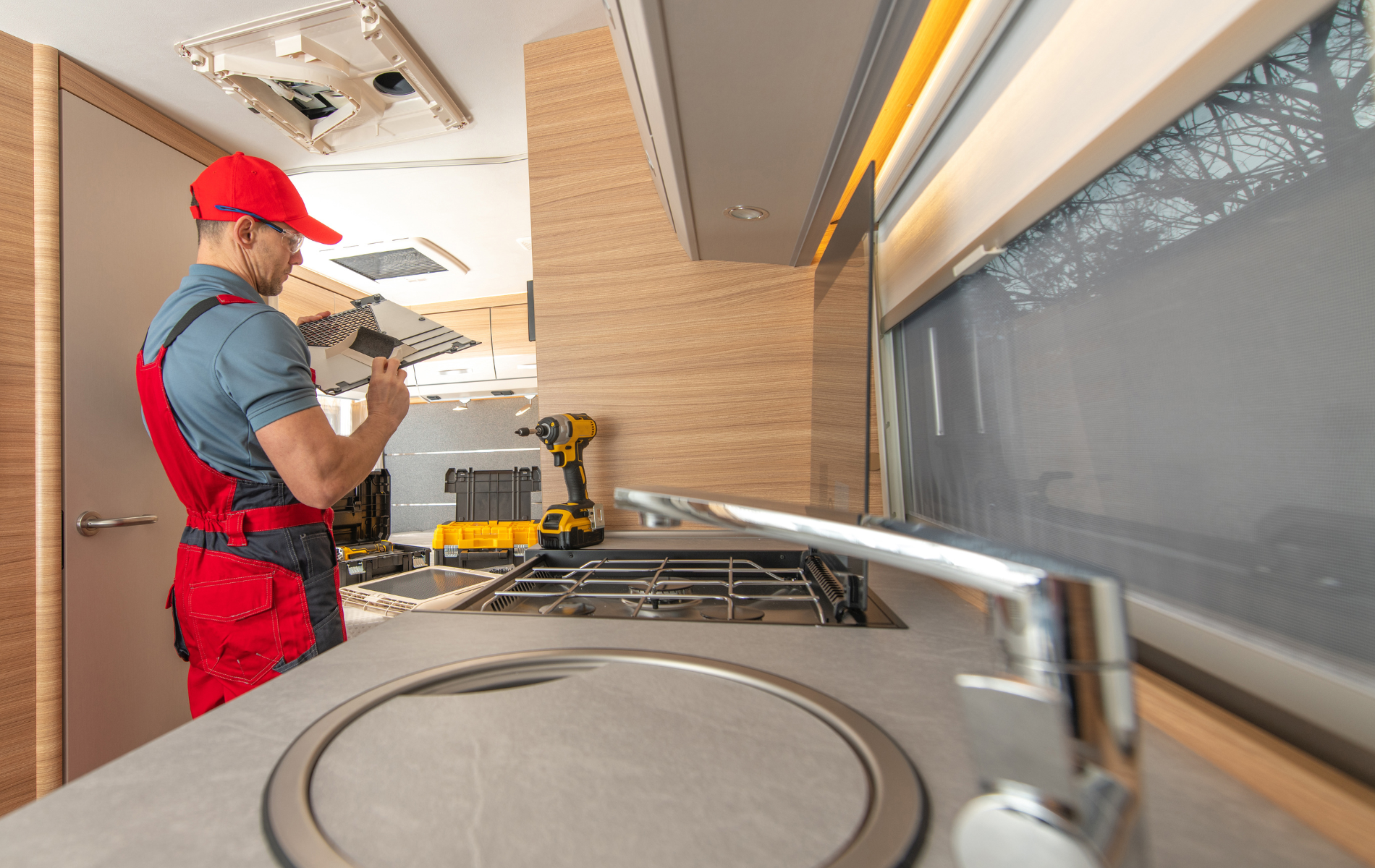 A man is working on a camper in a kitchen.