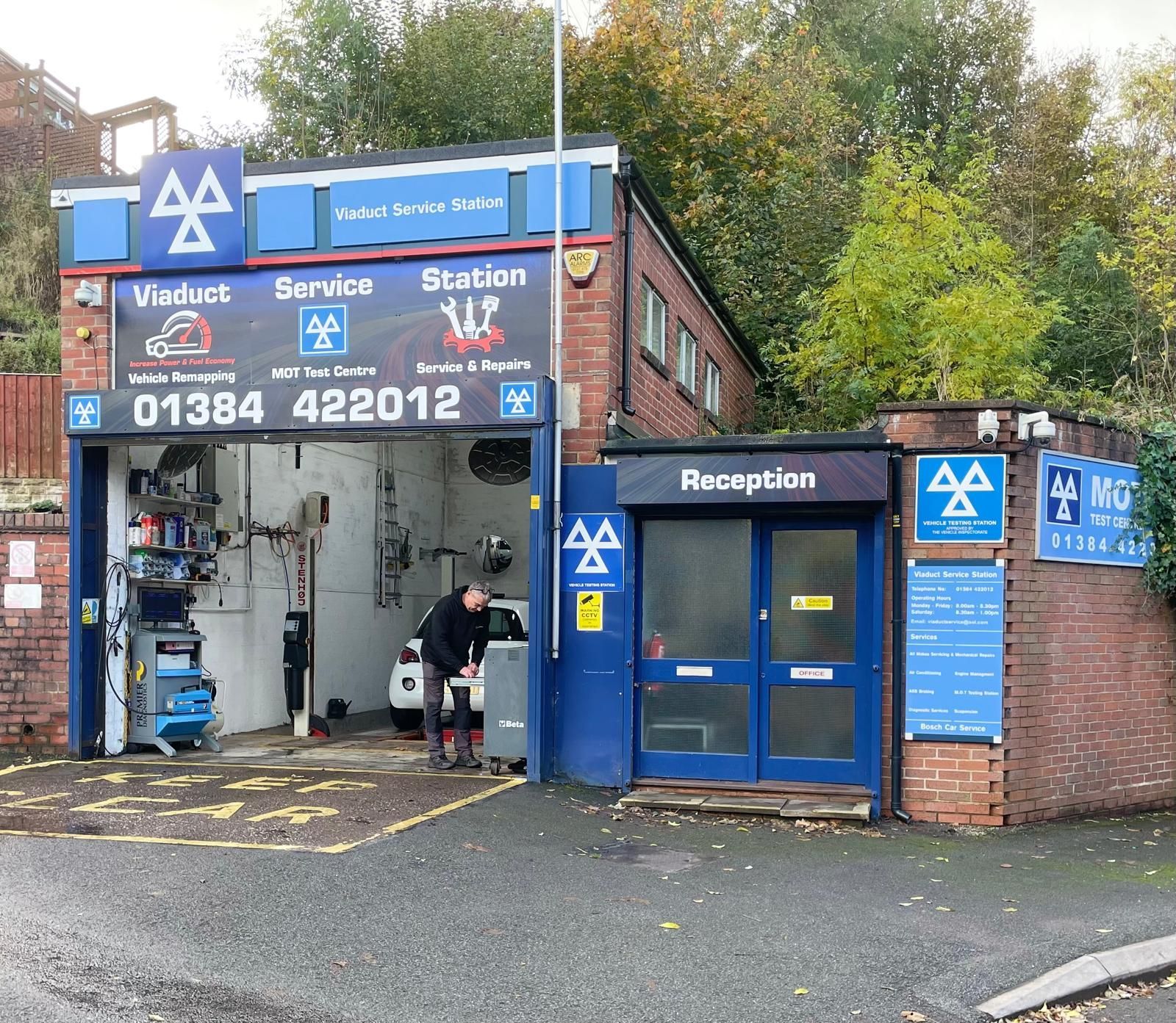 A man is working on a car in front of a aa garage