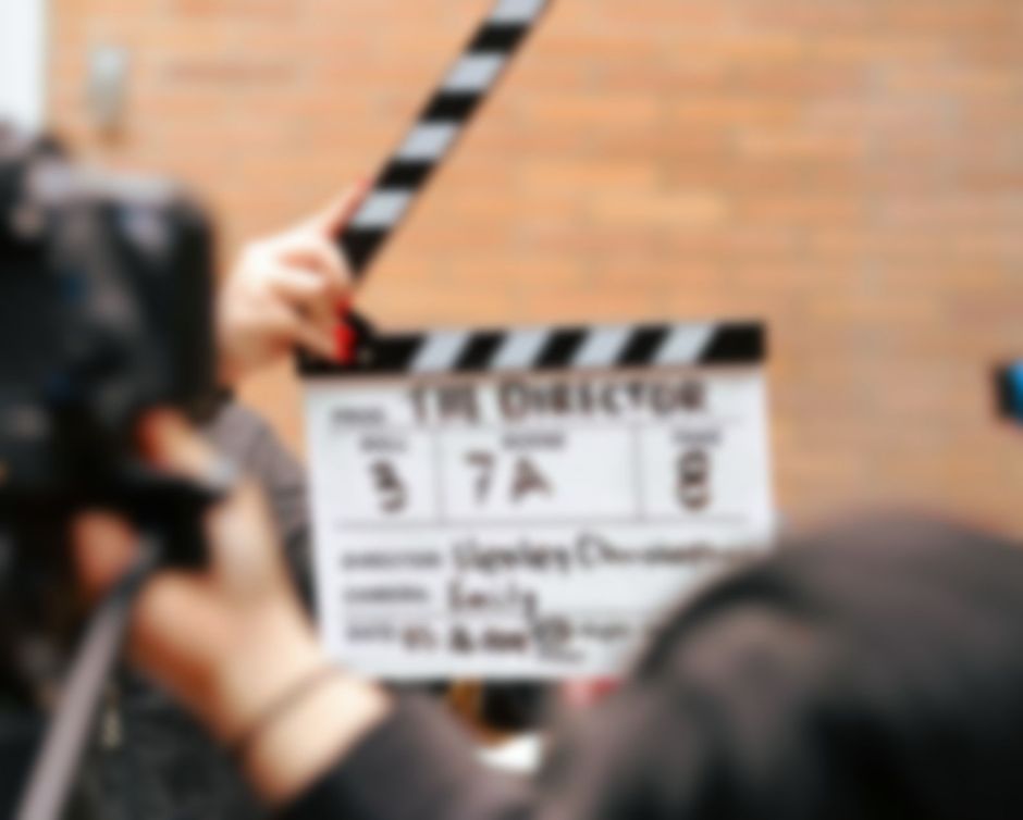 A person is holding a clapper board in front of a camera.