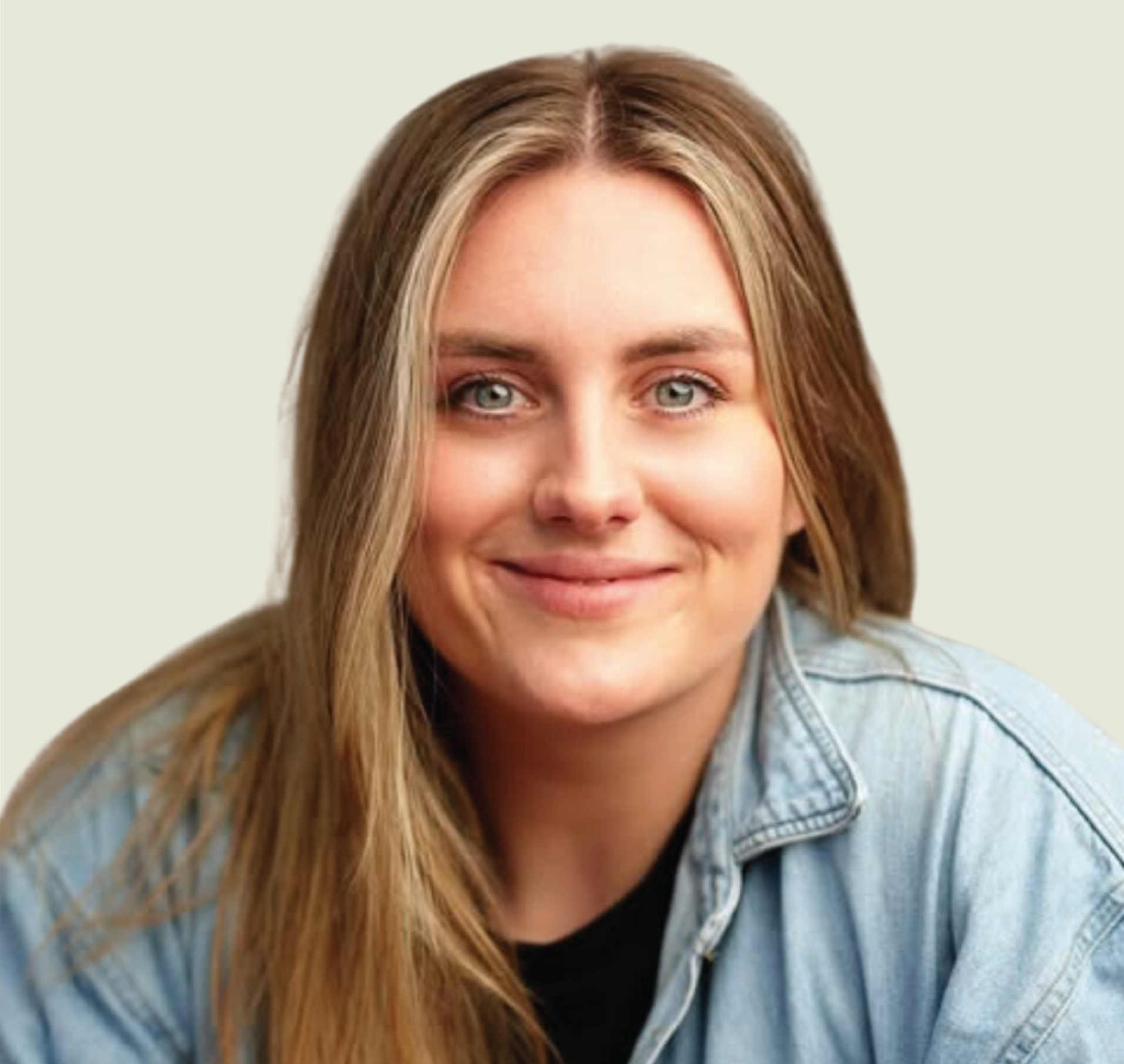 A woman wearing a denim shirt and a black shirt is smiling for the camera.