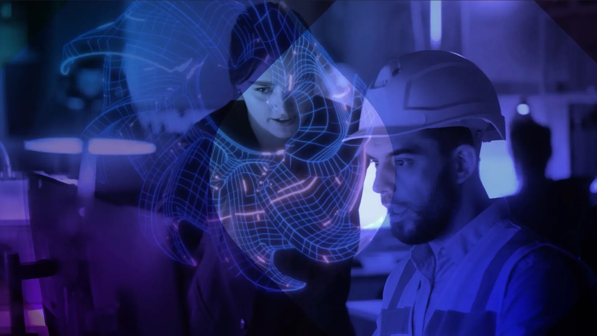An adviser leans into an operative in conversation as they look at a screen.