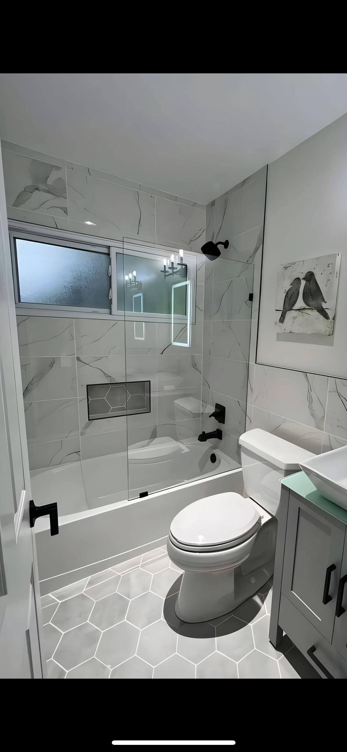 A modern bathroom with white marble-look tiles, a bathtub, toilet, and sink. Black fixtures.