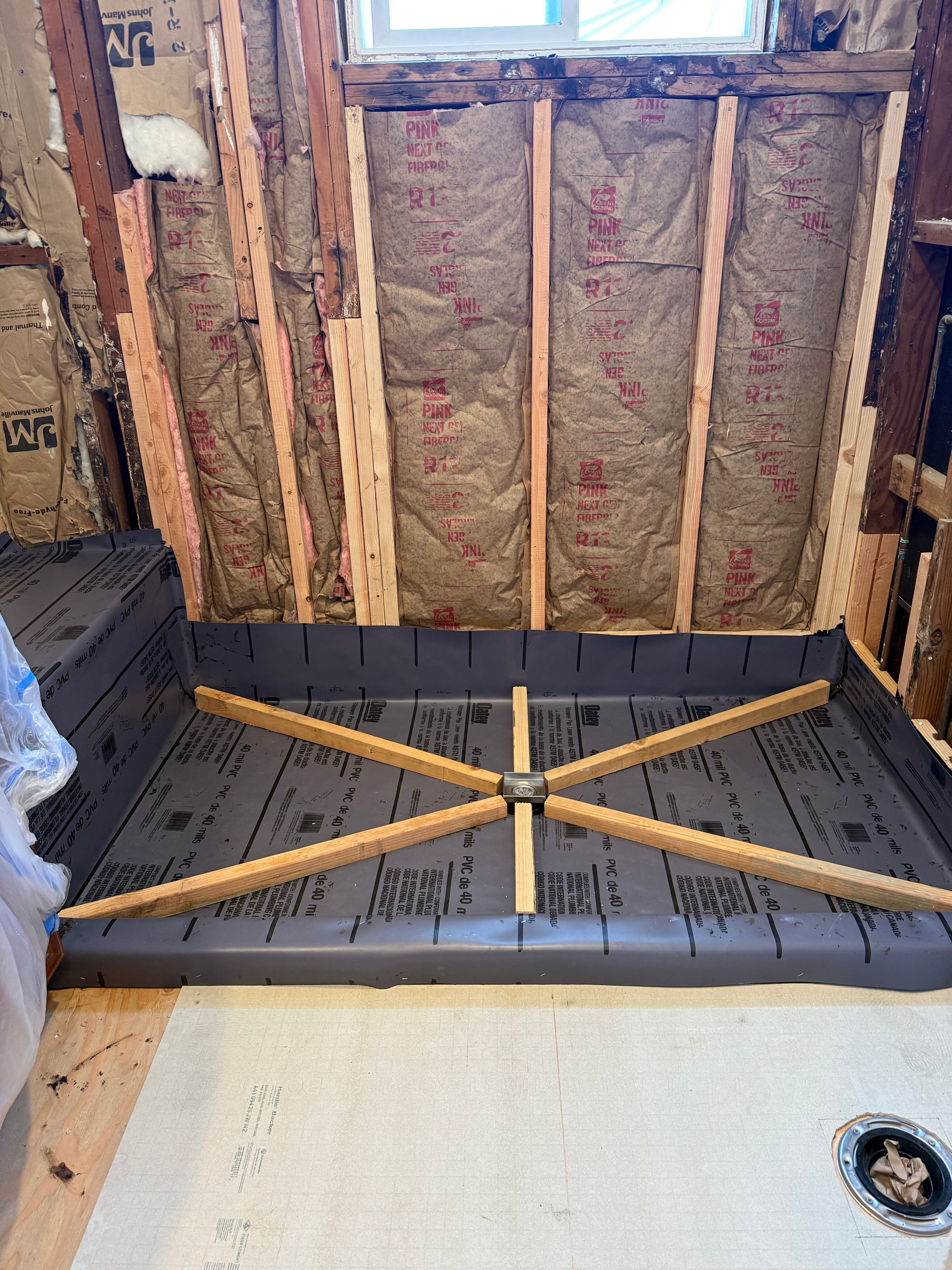 Shower pan with wooden supports installed, ready for tiling. Insulation and wood framing visible.