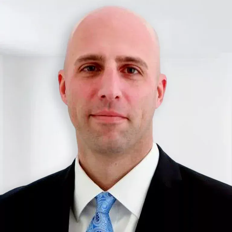 Bald man in a suit and tie, looking forward with a neutral expression.