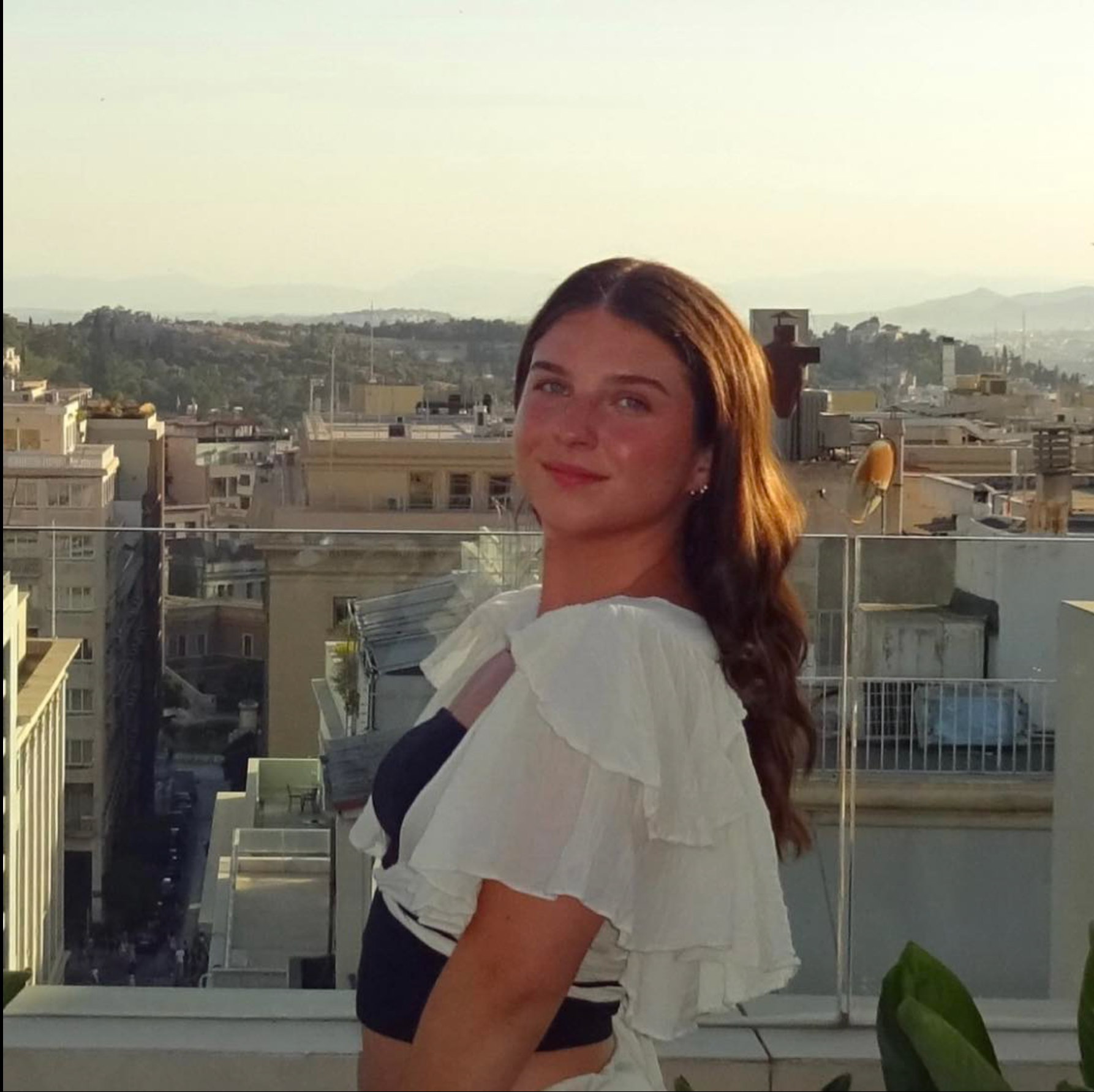 A woman is standing on a balcony overlooking a city
