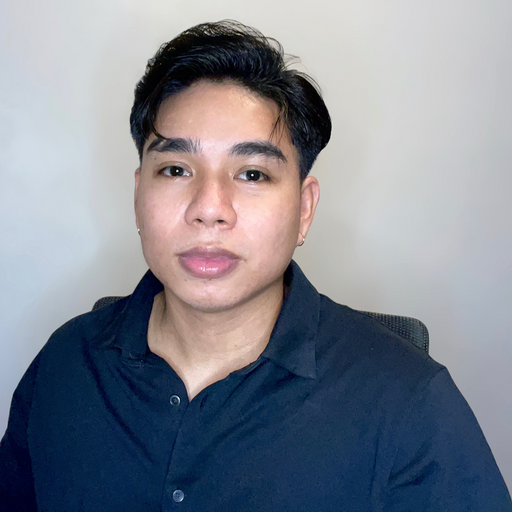 A young man in a black shirt is sitting in a chair and looking at the camera.