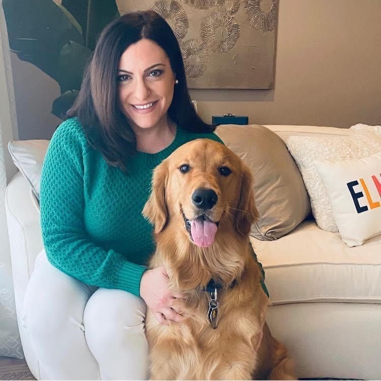 A woman in a green sweater is sitting on a couch with a dog.