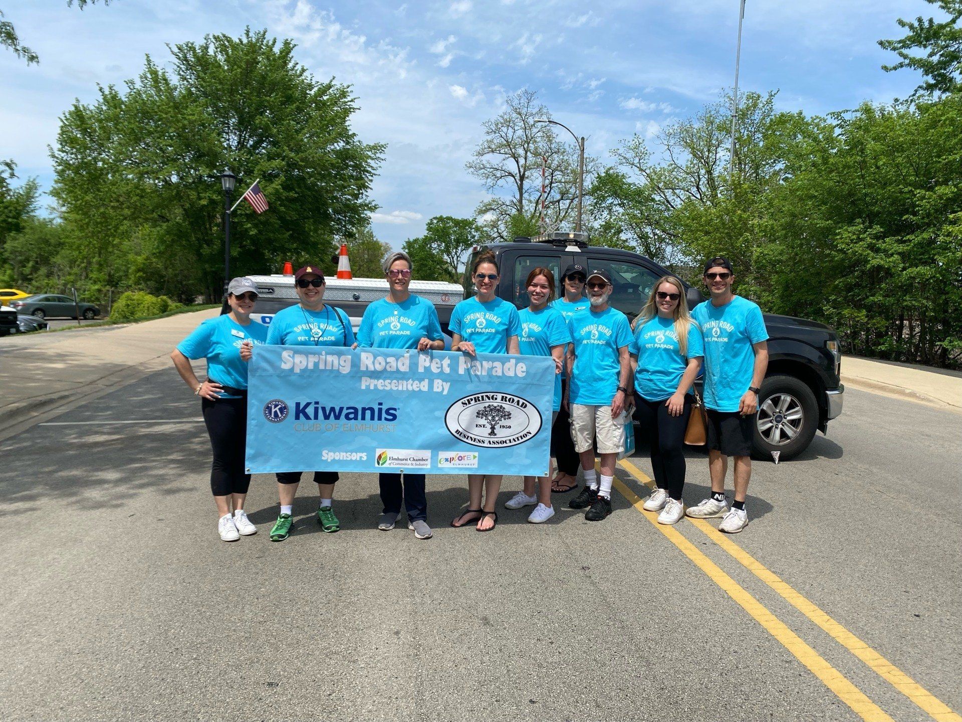 A group of people standing on the side of a road holding a sign.
