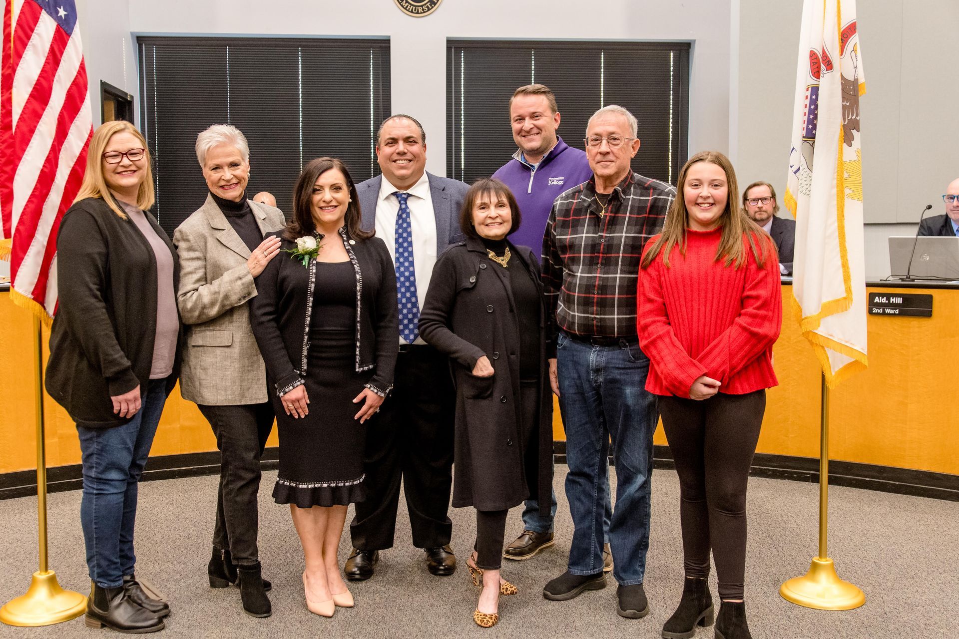 A group of people are posing for a picture in front of american flags.