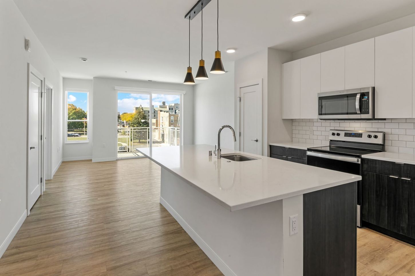 Modern kitchen with white countertops, dark cabinets, and stainless steel appliances.