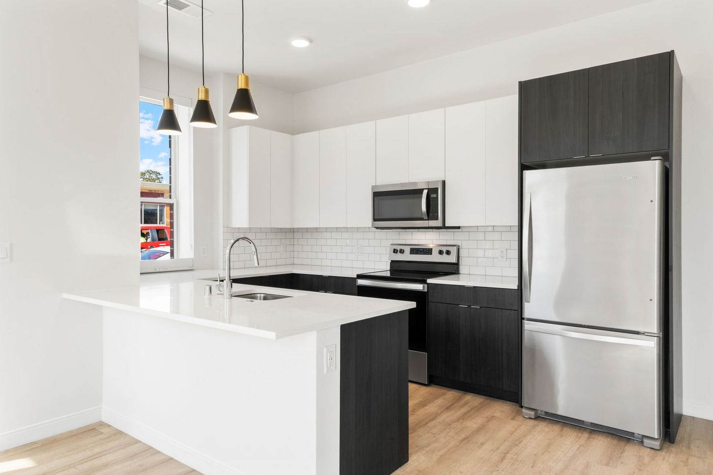 Modern kitchen with white and black cabinets, stainless steel appliances, and a breakfast bar.