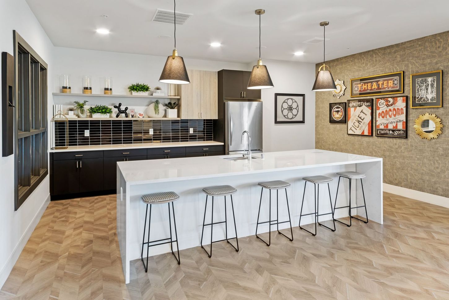 Modern kitchen with large island, stools, stainless steel appliances, and decorative accents.