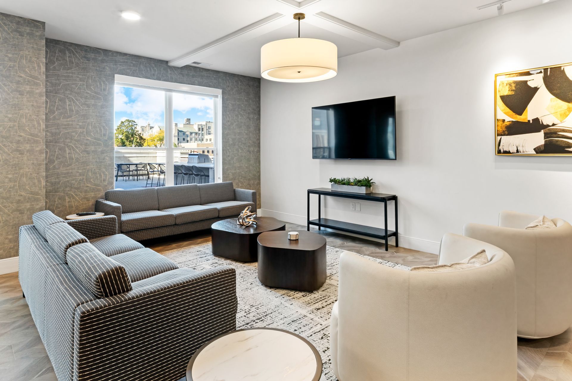 Modern living room with seating, TV, and decorative art. Neutral colors with accents of black and yellow.