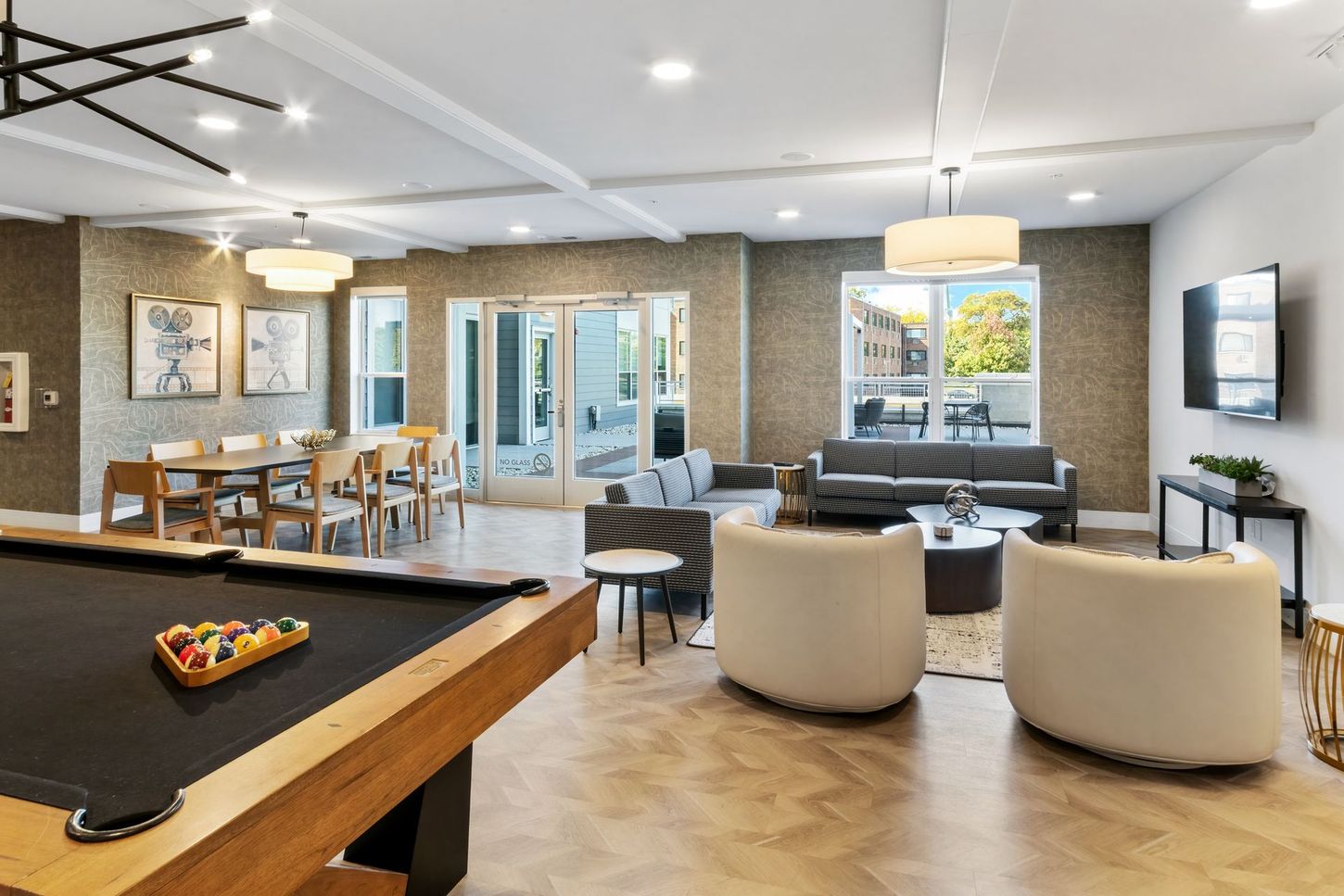 Spacious lounge with pool table, dining table, seating area, and sliding glass doors to outdoor patio.