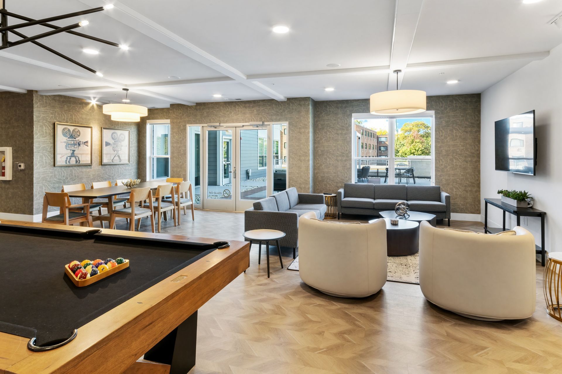 Spacious lounge with pool table, dining table, seating area, and sliding glass doors to outdoor patio.